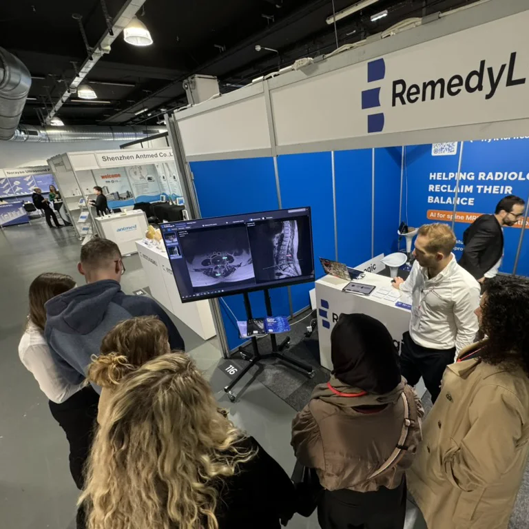 visitors round a monitor at a trade-show stand, the slices with the findings on screen